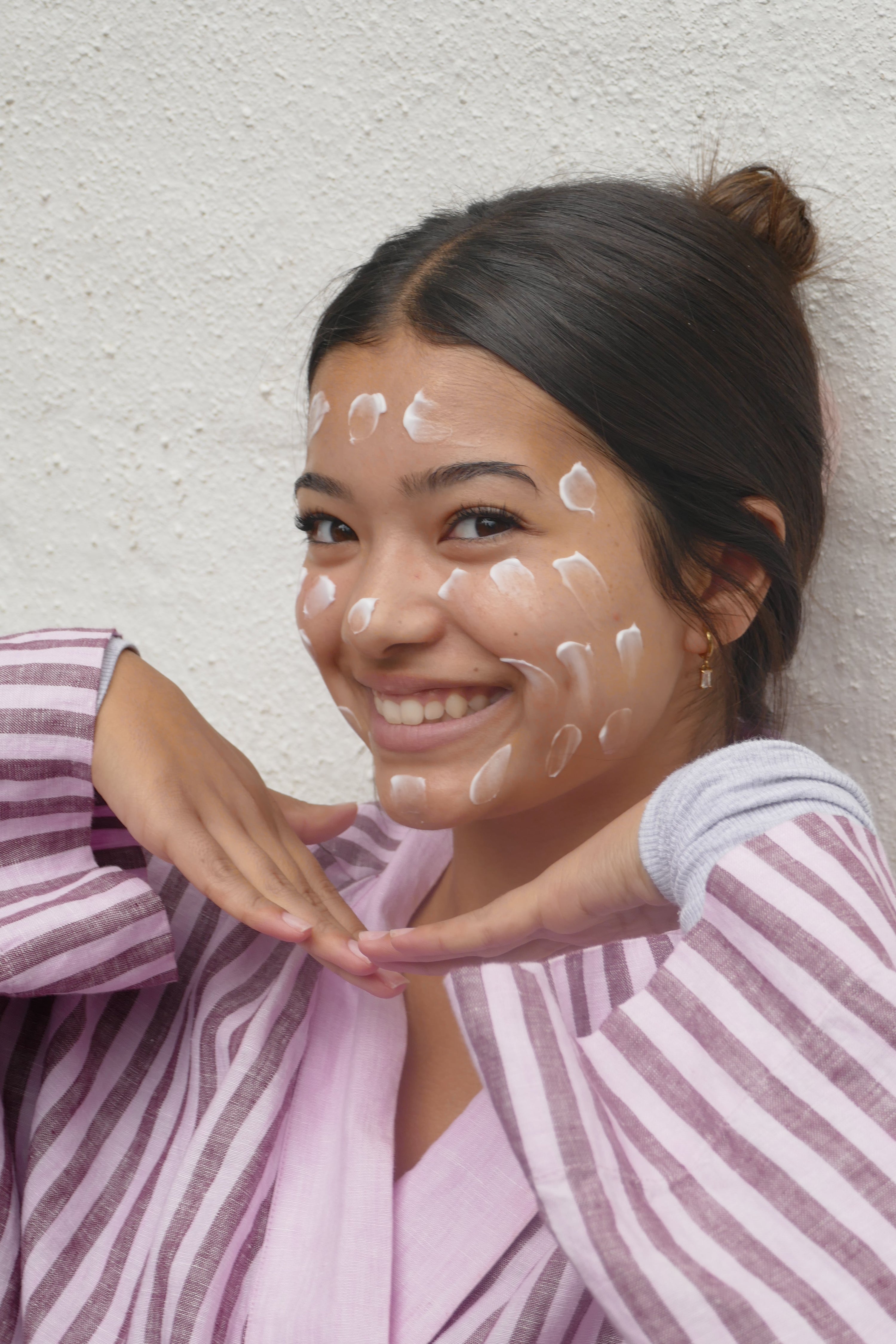 Young woman with moisturiser dots on face smiling — skin barrier care for teens and tweens by alcheMe